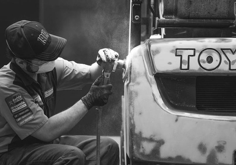 Technician reconditioning a used Toyota forklift. 